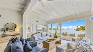 A spacious living room with a large window overlooking a body of water, furnished with sofas and a coffee table. - 4 Bed / 4 Bath with Stunning Views of Bimini Bay ! (Anna Maria)