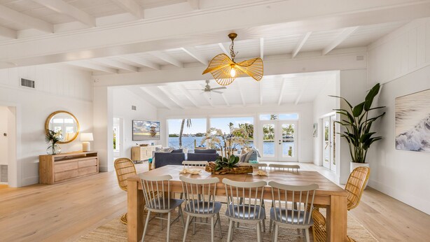 A spacious dining area with a wooden table and chairs, a ceiling fan, and a view of the ocean. - 4 Bed / 4 Bath with Stunning Views of Bimini Bay ! (Anna Maria)