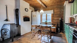Una cocina rústica con vigas de madera, una mesa de comedor con sillas, una lámpara colgante y una ventana con vistas.