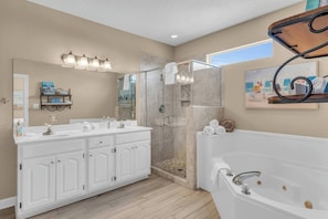 Un baño moderno con cabina de ducha, tocador doble con espejo grande y bañera independiente.