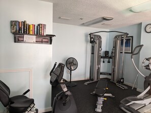 A home gym with exercise equipment, a fan, and a bookshelf with books.