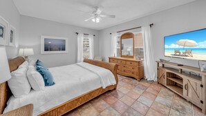 A bedroom with a bed, a dresser, a television, and a view of the beach. - Dandy Sandy: Sleeps 24 - Pets - Pools - Hot Tubs (Gulf Shores)