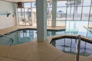 Una piscina interior con vistas despejadas a la playa y palmeras.