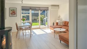 A modern living room with a fireplace, a dining table with chairs, a sofa, and a small coffee table. - Gorgeous apartment in Skagen with WiFi (Skagen)