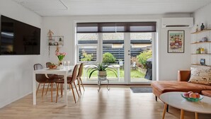 A modern living room with a dining area, a sofa, and a table with a bowl of fruit. - Gorgeous apartment in Skagen with WiFi (Skagen)