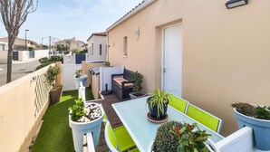 Un patio con una mesa y sillas, rodeado de plantas en macetas y un pequeño jardín.