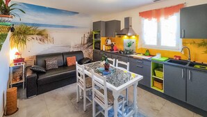 Un espacio habitable compacto con kitchenette, comedor y sofá.