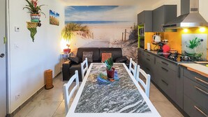 Un comedor con un mural de playa, una cocina equipada con electrodomésticos modernos y un rincón de estar acogedor.