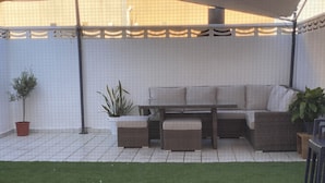 An outdoor patio area with a sofa set, a table, and potted plants. - Townhouse 300 meters from the sea (València)