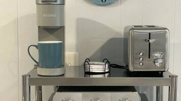 A kitchenette with a coffee maker, toaster, and a clock on the wall.