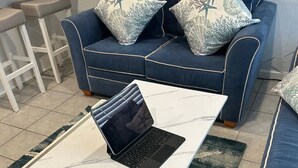 A modern living room with a blue sofa set, a white marble coffee table, and a laptop on the table. - Clean, modern and well-equipped Ocean City condo (Ocean City)