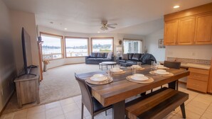 A spacious living area with a large dining table set for four, a sofa, and a view of the outdoors. - Sunset Lake Retreat@ Lake Tapps-Lakefront, Spacious, Sports court, Kayaks (Lake Tapps)