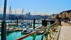 Un puerto deportivo con numerosas embarcaciones amarradas, un puente y edificios al fondo.