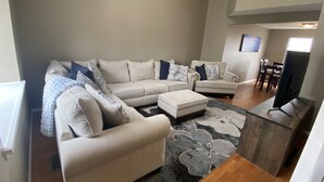 Ein Wohnzimmer mit einem Ecksofa, einem Couchtisch und einem Flachbildfernseher.