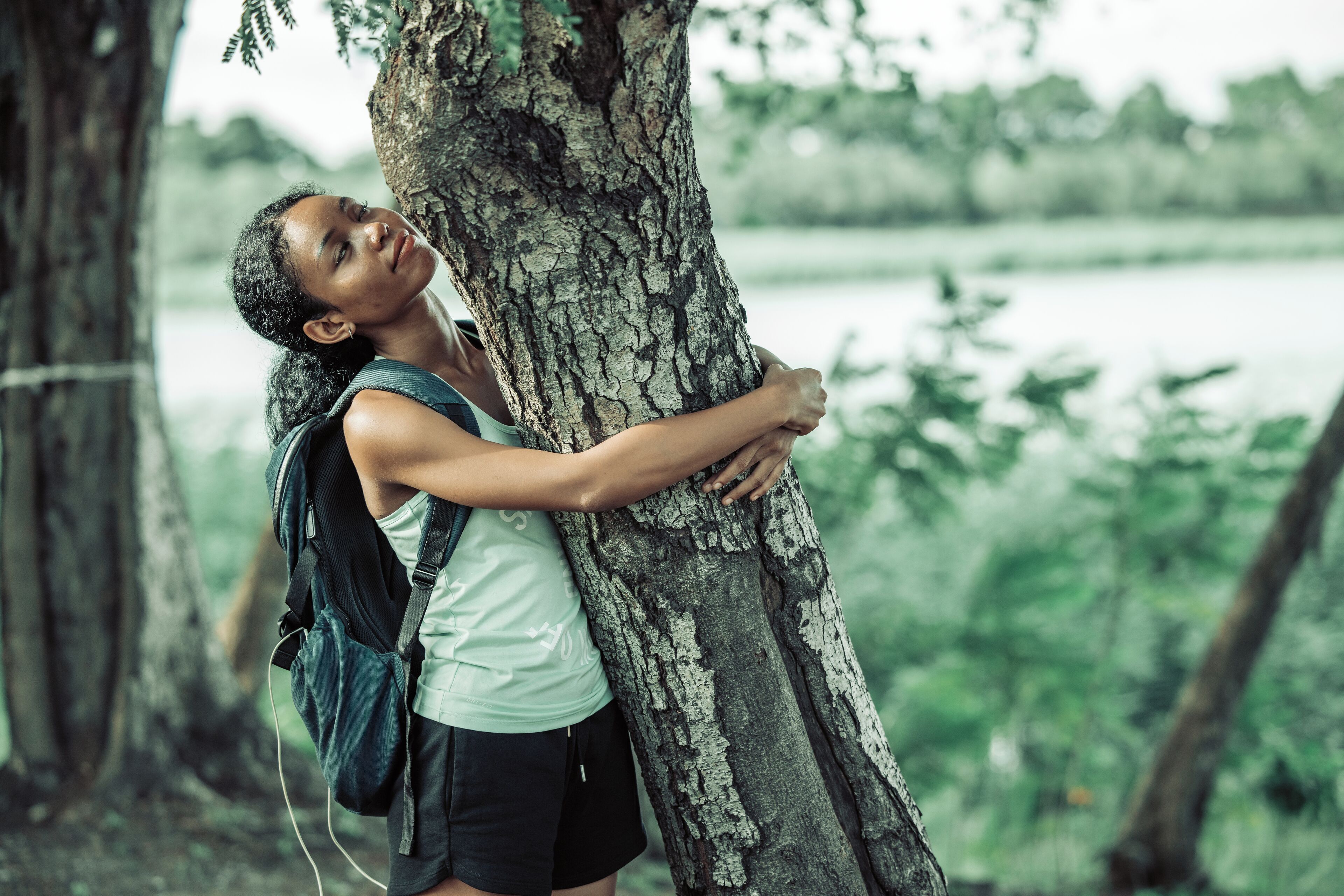 A person hugging a tree in a natural setting.