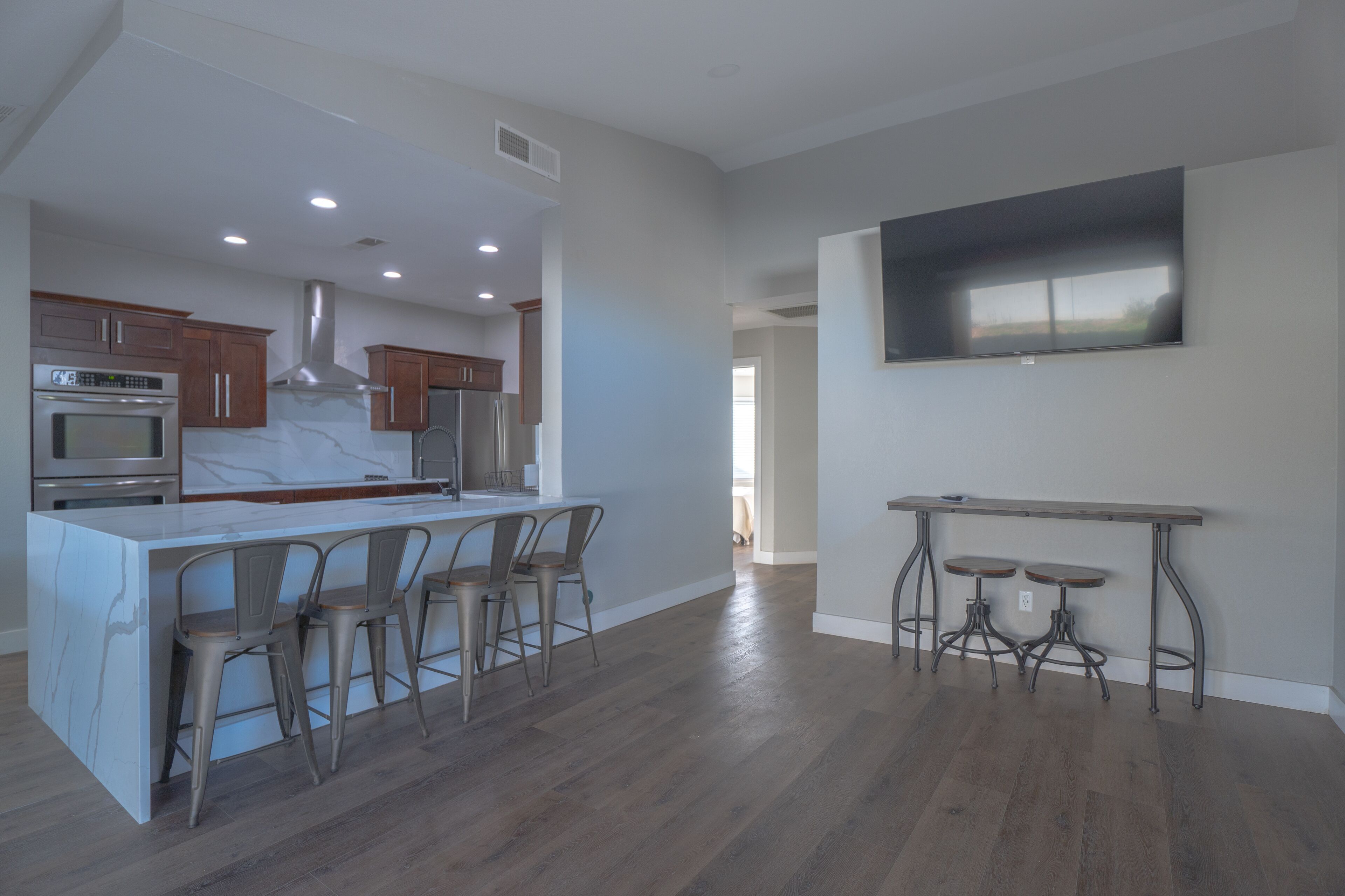 A modern kitchen with a marble island, stainless steel appliances, and a dining area with stools.