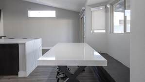 Une cuisine moderne dotée d’un long plan de travail, d’un îlot central intégré et d’une fenêtre laissant entrer la lumière naturelle.