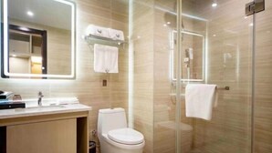 Uma casa de banho moderna com cabine de duche em vidro, sanita e toucador com espelho.