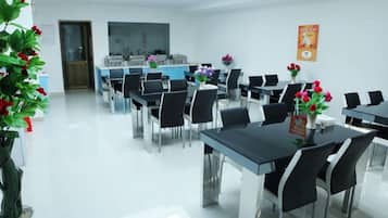 A conference room with multiple tables and chairs, a large window, and a door.