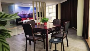 Quarto de hotel moderno com área de refeições, uma janela grande e um mural com vista para a cidade.