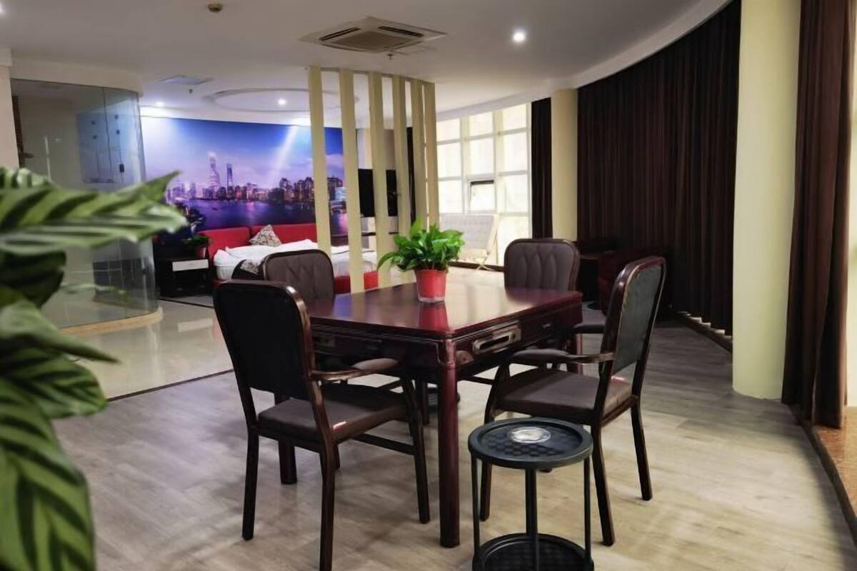 A modern hotel room with a dining area, a large window, and a cityscape mural.