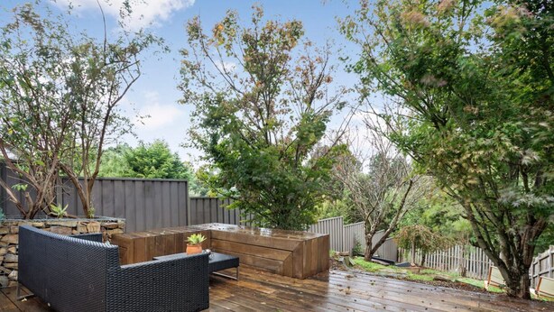 An outdoor deck with a built-in seating area, stone wall, and wooden deck flooring. - Jayda- **A split level home with a magical ambience ** (Daylesford)