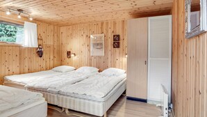 A wooden-paneled room with two beds, a window with a view of greenery, and a mirror on the wall. - Beautiful home in Saltum with kitchen (Saltum)