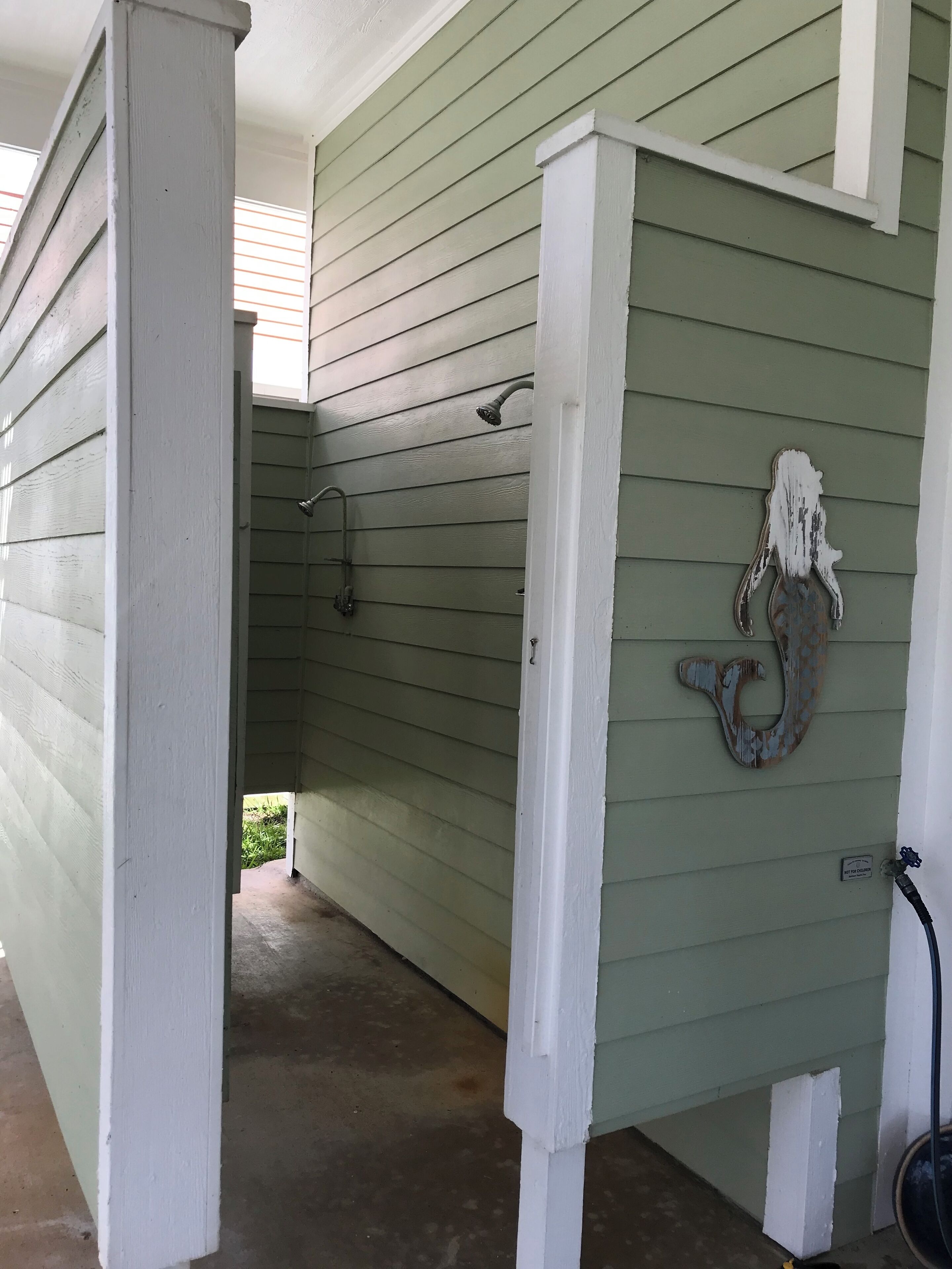 A covered porch with a metal horse sculpture, a hose, and a metal faucet.