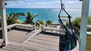 A wooden deck with a hammock and a bench overlooking a clear blue sea with a boat in the distance. - NEW POOL! Luxury waterfront! "Rainbow Charm" ***GAME ROOM!!*** (Rainbow bay)