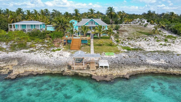 A coastal property with multiple buildings, a wooden dock, and clear turquoise waters. - NEW POOL! Luxury waterfront! "Rainbow Charm" ***GAME ROOM!!*** (Rainbow bay)