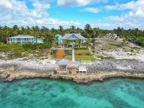 A coastal property with multiple buildings, a wooden dock, and clear turquoise waters.