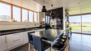 A modern kitchen with a large island, bar stools, and a view of the countryside. - 3 bedroom awesome home in Plélan-le-Petit (Plélan-le-Petit)