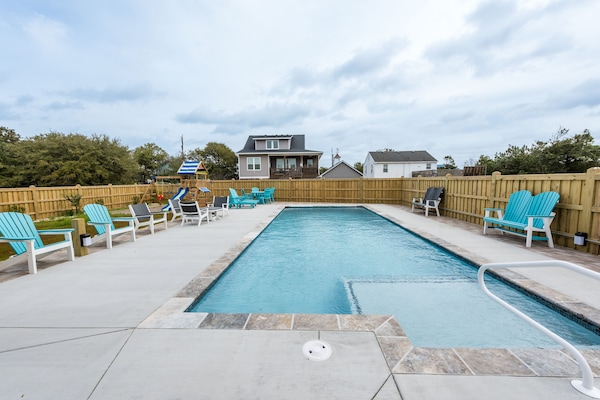 Large saltwater concrete pool with large sitting area with tables and chairs.