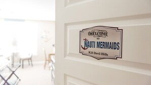 Une porte sur laquelle est affiché un panneau indiquant : « Bienvenue chez Nauti Mermaids, à Kill Devil Hills. »