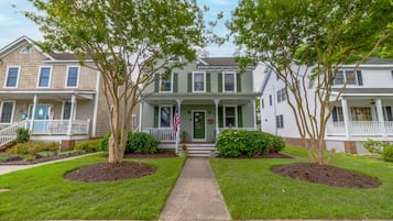 A two-story house with a front porch, a flag, and a well-maintained lawn.