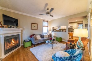 A living room with a fireplace, a sofa, a coffee table, and a television. - Golf cart included! 5 blocks to the beach, and in historic district! (Cape Charles)
