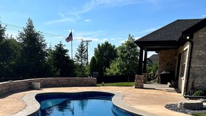 A swimming pool with a curved edge, surrounded by a stone patio.