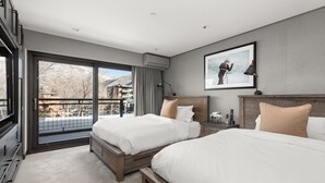 Une chambre d’hôtel avec deux lits, une grande fenêtre donnant sur les montagnes, un tableau accroché au mur et un appareil de climatisation fixé au plafond.