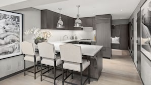 Une cuisine moderne dotée d’un îlot central, de luminaires suspendus et d’un coin repas avec des chaises.