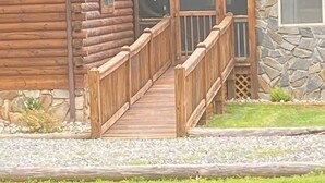 A log cabin with a wooden deck and stone exterior. - Cozy log cabin, centrally located with covered storage for an RV/Boat (Stanley)