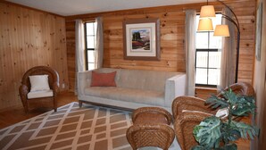 A cozy room with a sofa, two armchairs, a coffee table, and a floor lamp. - Cozy log cabin, centrally located with covered storage for an RV/Boat (Stanley)