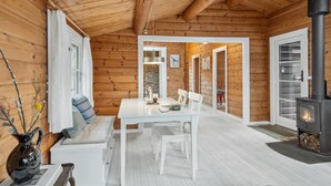 Een gezellig blokhutinterieur met een eethoek, een bank, een open haard en een stenen muur.