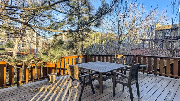 A wooden deck with a table and chairs, surrounded by trees and a fence. - Single-family home steps from Boulder's Greenbelt (Boulder)