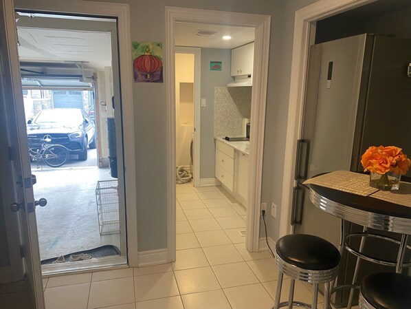 A kitchen with a refrigerator, a sink, and a dining area with stools.