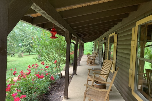 Welcome to the Lodge with porch lined with rocking chairs and roses