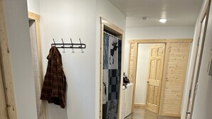 Un pasillo con un perchero, una mesa y una puerta que da a una habitación.