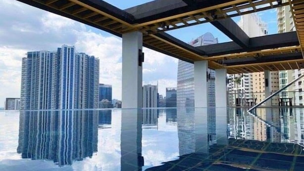 Una piscina interior moderna con suelo de vidrio, rodeada de edificios altos.