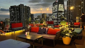Un bar en la azotea con asientos y mesas, rodeado de edificios de la ciudad.