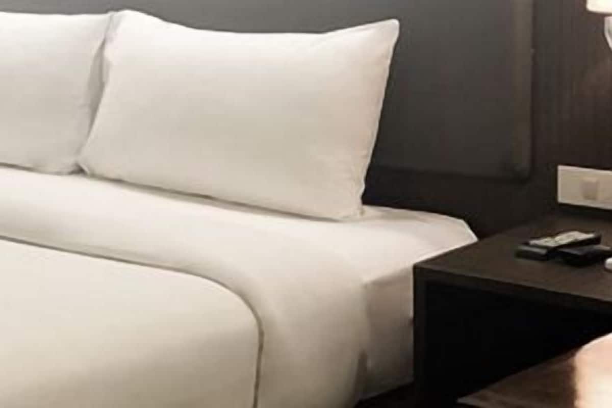 A neatly made bed with white linens in a hotel room.