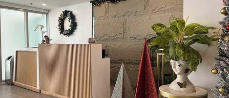 Un espace d’accueil au design moderne, comprenant un comptoir de réception, une couronne décorative accrochée au mur et un sapin de Noël.